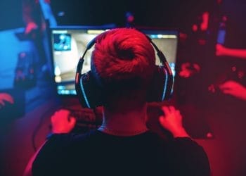 Professional gamer playing online games tournaments pc computer with headphones, Blurred red and blue background.