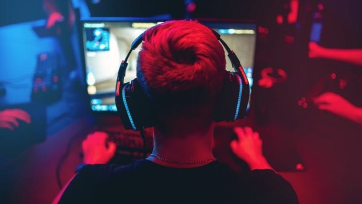 Professional gamer playing online games tournaments pc computer with headphones, Blurred red and blue background.