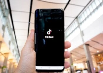 person holding black android smartphone - Hand of man holding mobile phone opening Tik Tok application, in shopping mall. , tags: tiktok de l'ia par - unsplash