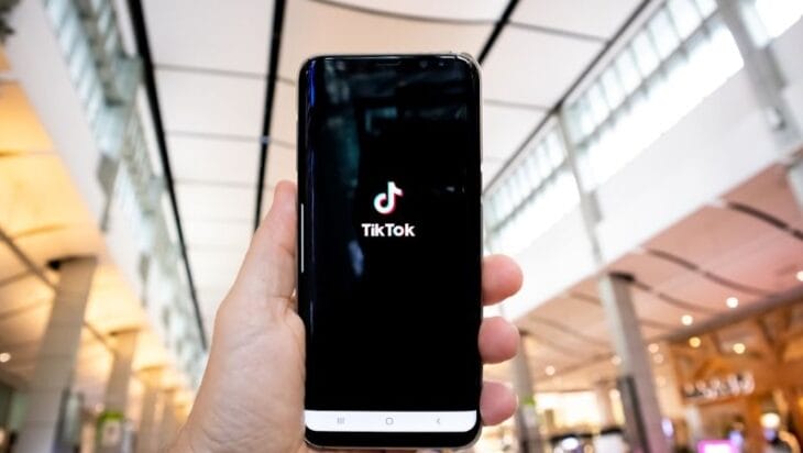 person holding black android smartphone - Hand of man holding mobile phone opening Tik Tok application, in shopping mall. , tags: tiktok de l'ia par - unsplash